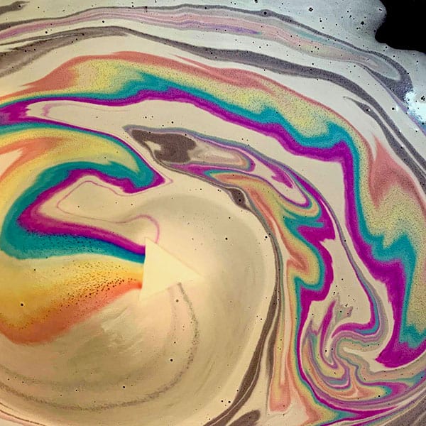 Rainbow Prism Bath Bomb - White bath bomb dissolving in water with colorful swirls